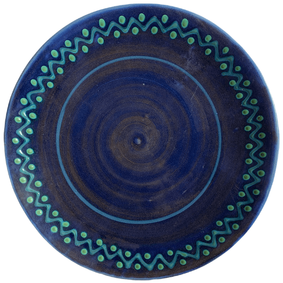 Pottery design with blue background with turquoise zig zags and green dots.